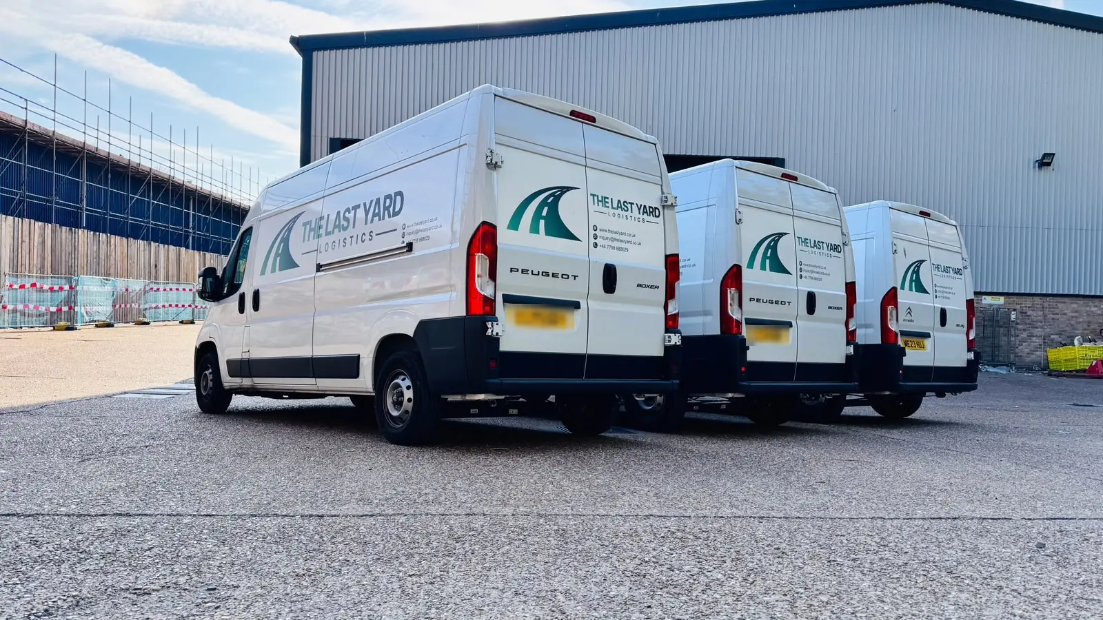 Rear view of three The Last Yard Logistics vans parked at the warehouse